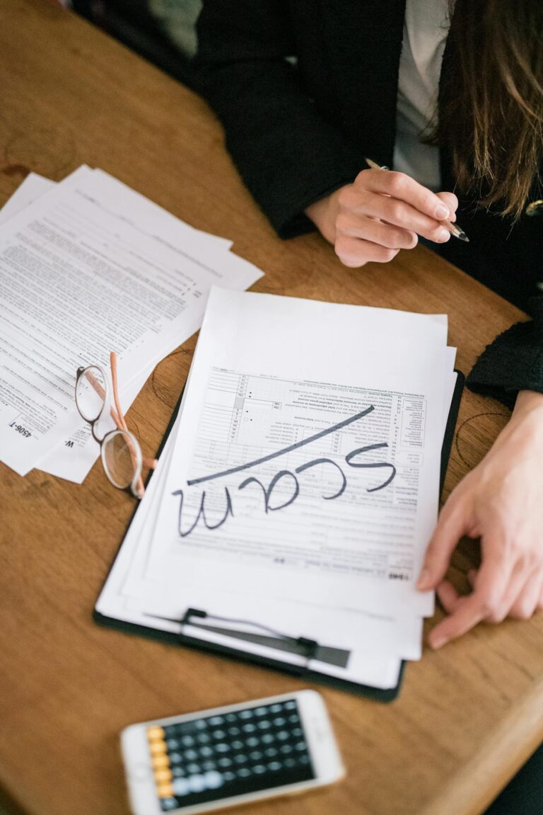Close-up of hands reviewing suspicious tax documents labeled 'scam' on a desk.