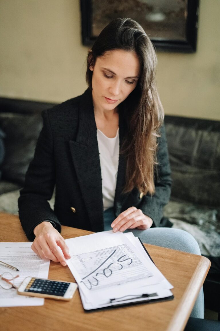 Woman examines financial documents at desk, marking potential scam.